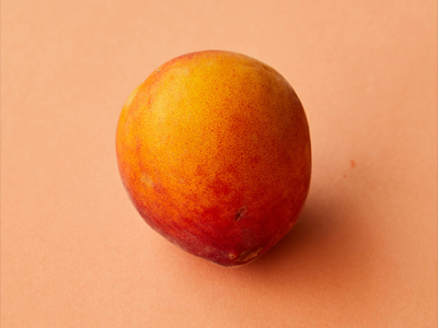Three apricots creatively stacked atop an ice cream cone against a black background.